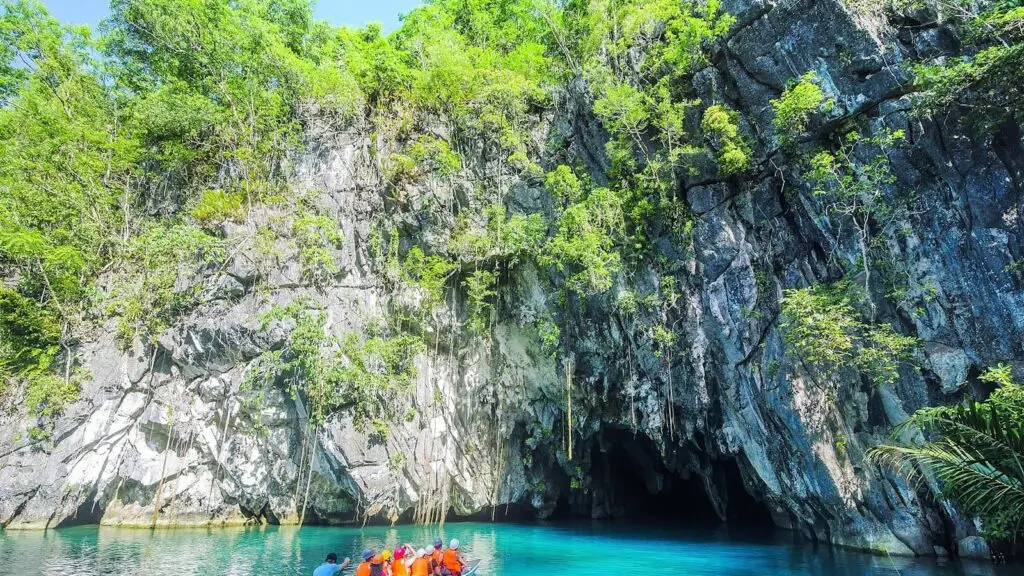 A boat of visitors below limestone cliffs at the Puerto Princesa Subterranean River National Park, Palawan