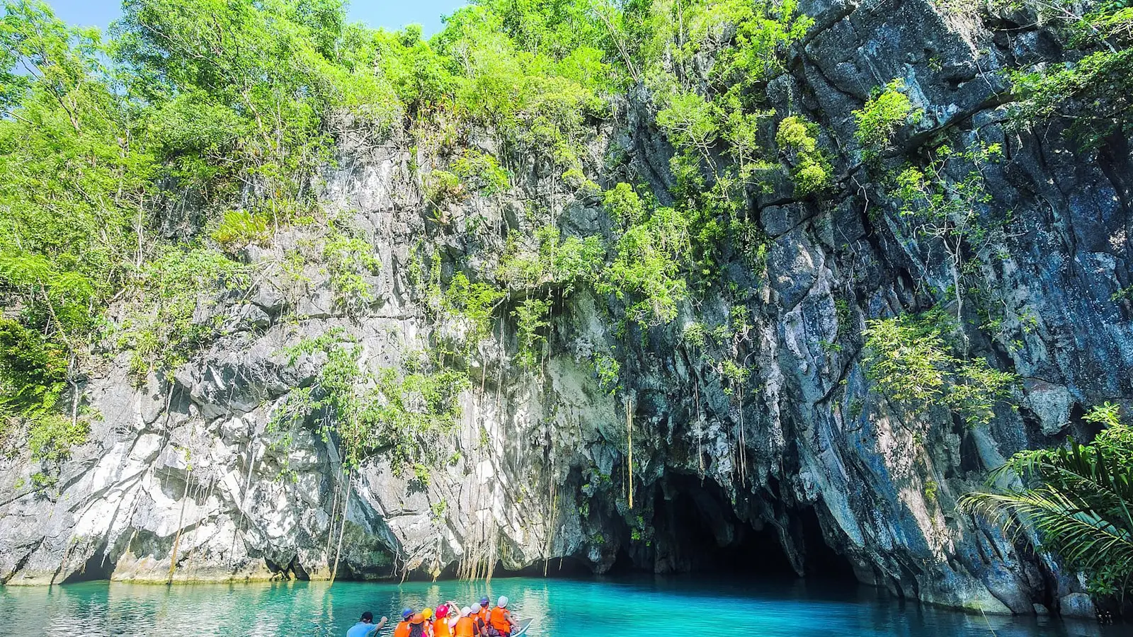 A boat of visitors below limestone cliffs at the Puerto Princesa Subterranean River National Park, Palawan