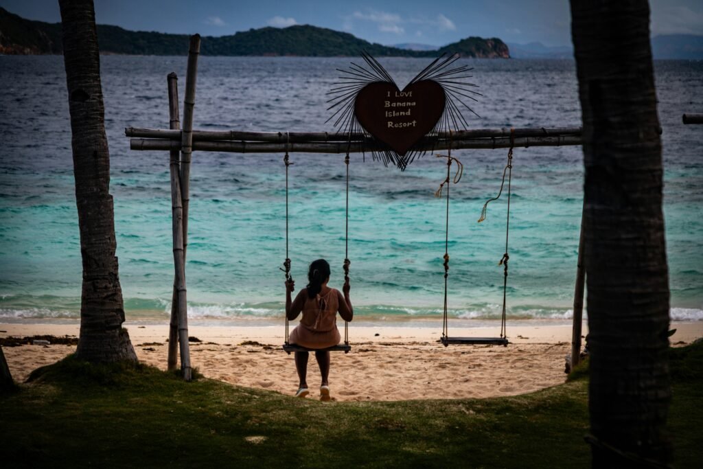 Palm trees and a beach swing over turquoise water at Bulalacao, Coron, Palawan, Philippines